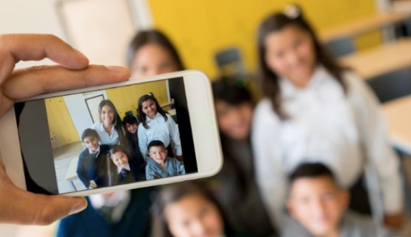 teacher and students being photographed by a mobile device